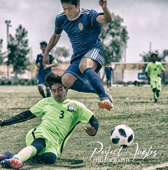 Soccer player leaping over a sliding tackle