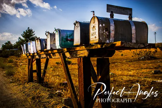 Row of weathered rural mailboxes at sunset
