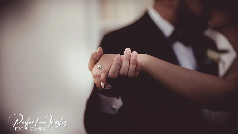 Close-up of a bride and groom holding hands